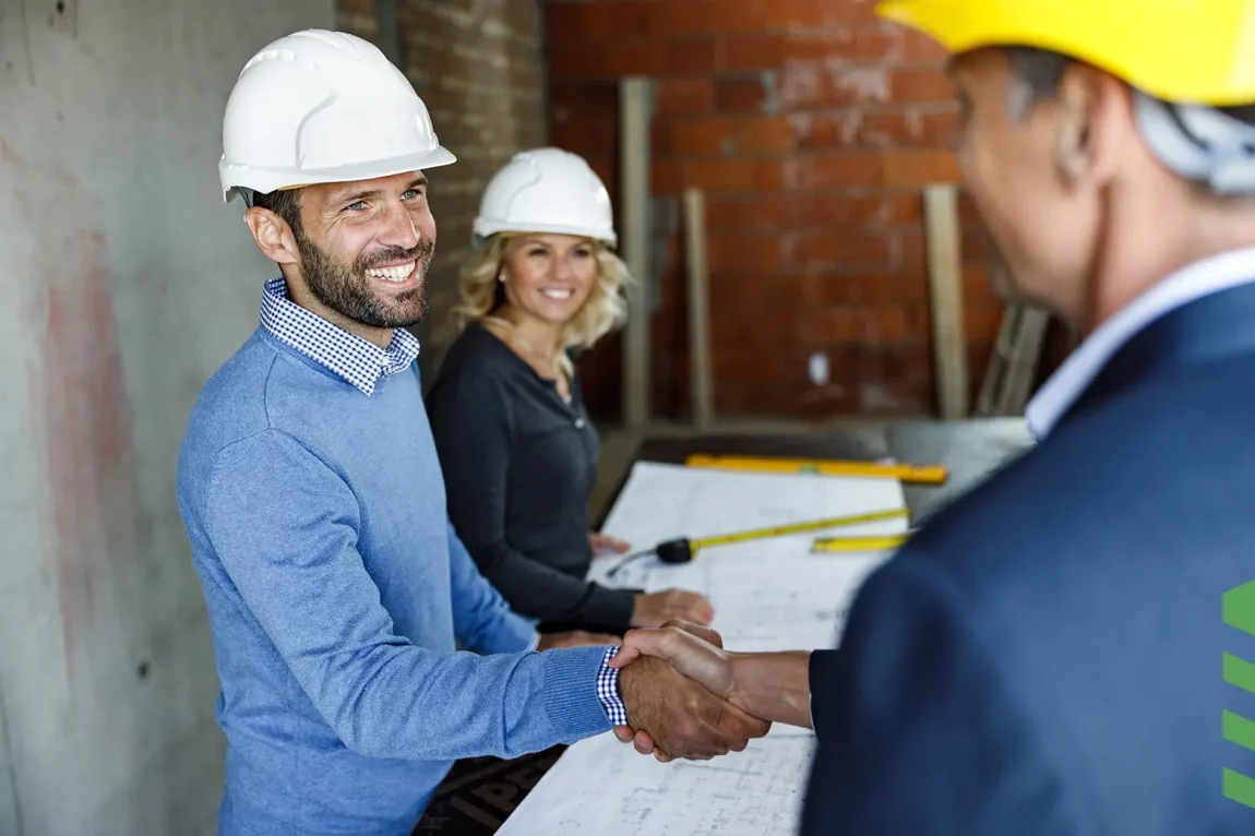 2 personnes se serrant la main dans un chantier de construction.